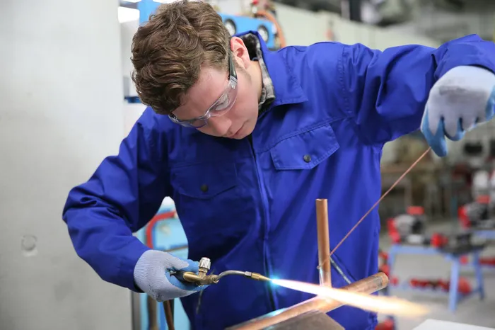 copper pipe being soldered together by a plumber
